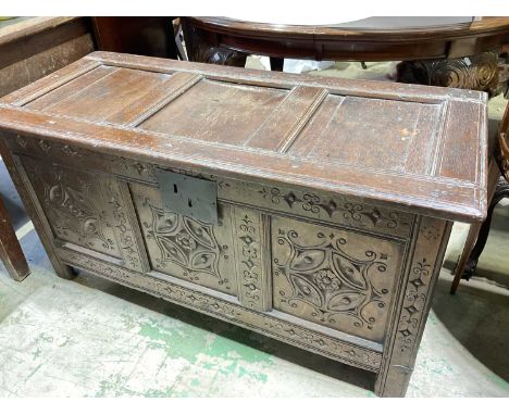 An early 18th century oak coffer with triple panel hinged lid, carved front detail, and raised on stile supports, width 127cm