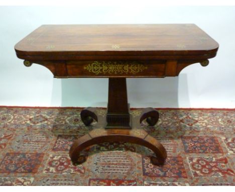 A Regency Rosewood and Brass Inlaid Card Table, the hinged top enclosing a baize lined interior above a brass inlaid frieze, 