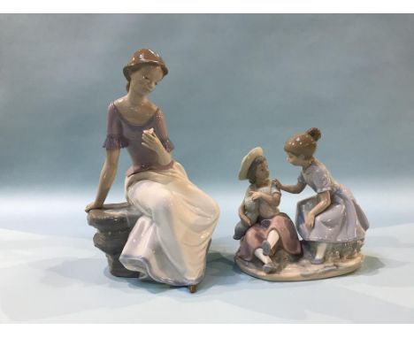 A Nao figure of a seated girl, number 1392, 29cm height and another group of two children holding a baby, 19cm height