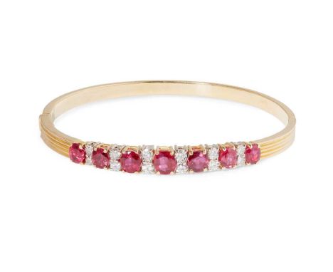 A ruby and diamond bangle the hinged reeded bangle, claw-set with seven cushion-cut rubies and pairs of brilliant-cut diamond