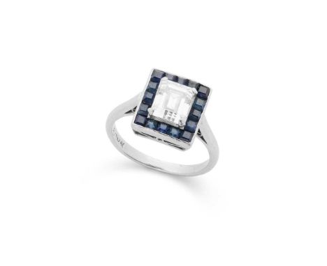 A diamond and sapphire cluster ring claw-set with a cut-cornered rectangular-cut diamond, in a channel-set border of square s