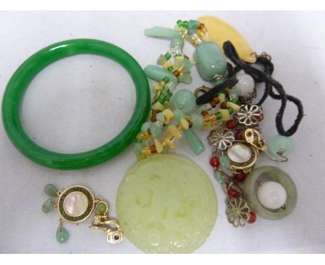 A chinese hard stone ring; a circular plaque decorated with a stylised dragon; a jade green coloured bangle and other items (