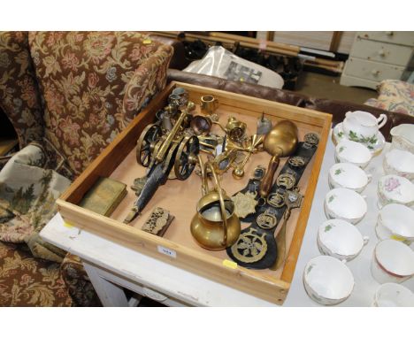 A wooden tray with contents of various brass ware to include horse brasses, model cannon, ornaments etc.