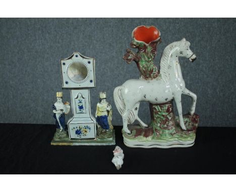 Staffordshire porcelain figures. A candleholder in the shape of a horse, a grandfather clock pocket watch stand and a Punch c