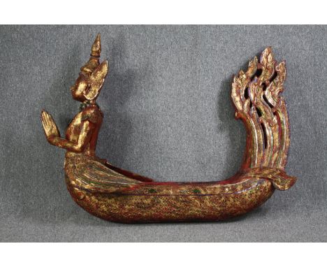 A large carved Buddha in a boat or canoe. Gilded and decorated with small mirror tiles. H.125 W.150 D.44 cm. 