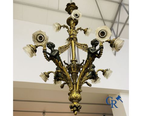 Chandelier: A large gilded and patinated bronze chandelier in empire style with 12 light points of which 4 arms with 2 light 