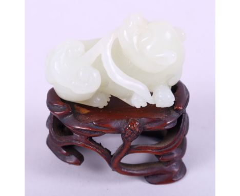 A Chinese pale celadon jade carved figure of a dog, 1 3/4" long, on carved hardwood standCondition:No apparent condition issu