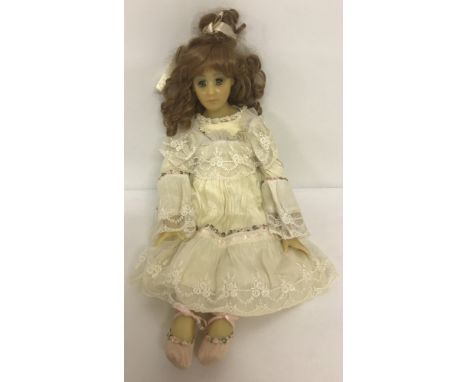 A modern blue eyed wax doll with wired soft body and legs in a traditional vintage style outfit.