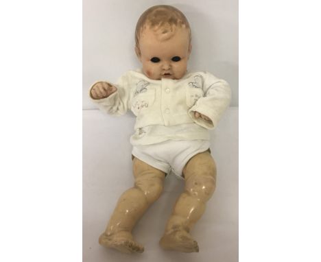 A soft body vintage composition baby doll with closing eyes, open mouth and two top teeth. Face shows signs of cracking.