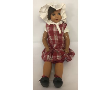 A large vintage composition doll. Jointed body, painted eyebrows and lips with open mouth. In a red pinafore dress.