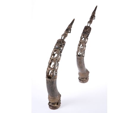 A PAIR OF BENIN BRONZE ROYAL HEAD TRUMPETS, each pierced and cast with figures and animals. Taller 56.5cm