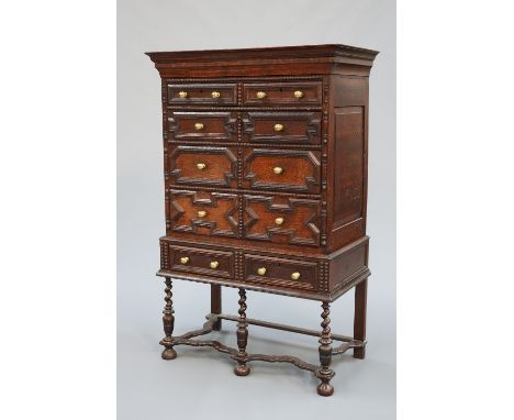 A 17TH CENTURY STYLE OAK CHEST ON STAND, 19TH CENTURY, the upper section with concealed drawer over two short above three lon