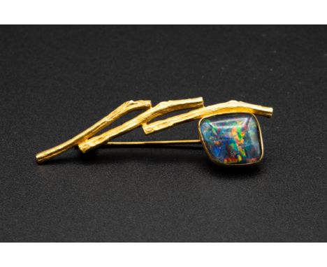 AN OPAL AND GOLD BROOCH, set with an abstract square cut opal on textured metal work strands, on brooch pin fitting. Stamped 