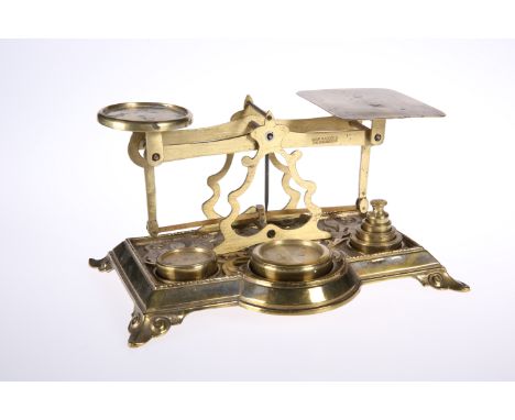A SET OF VICTORIAN BRASS POSTAL SCALES, the beam stamped WARRANTED ACCURATE, the decorated base with six weights, 22.5cm wide