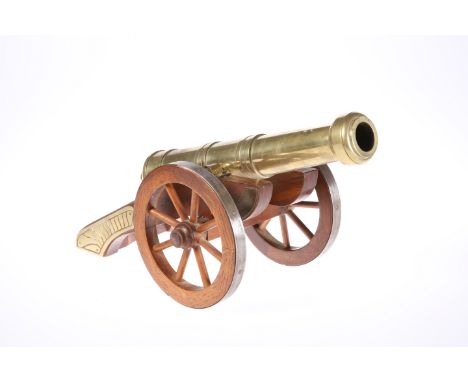 A DECORATIVE BRASS MODEL CANNON, the barrel moving on a wooden carriage, the wheels mounted in white metal. Length overall 42