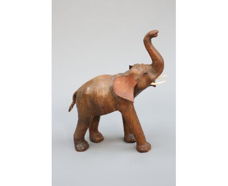 A VINTAGE LEATHER FIRESIDE MODEL OF AN ELEPHANT, modelled with truck aloft. 75cm high