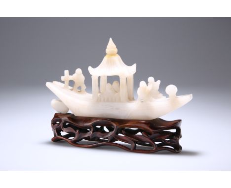 AN EARLY 20TH CENTURY CHINESE JADE MODEL OF A RIVER BOAT, on a wooden stand, the stone of grey-white hue. The jade itself 20c