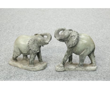 A PAIR OF CARVED STONE MODELS OF ELEPHANTS, each modelled with trunk raised above the head. 26cm high