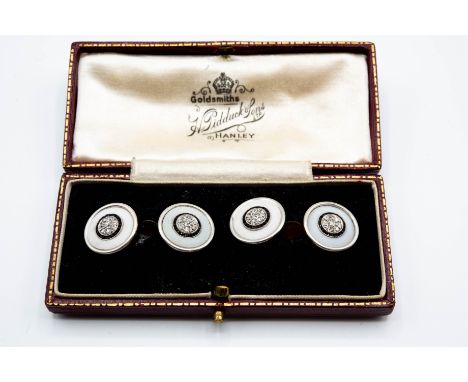 A PAIR OF DIAMOND, ENAMEL AND BLACK ONYX CUFFLINKS, each circular plaque with textured white enamelling set to the centre wit