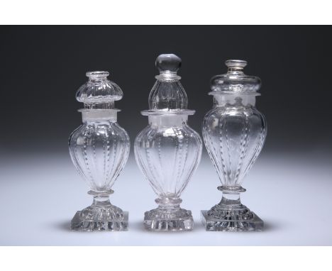 THREE ENGLISH GLASS CONDIMENT BOTTLES AND STOPPERS, CIRCA 1800, each with "lemon squeezer" base. Tallest 15.5cmGood condition
