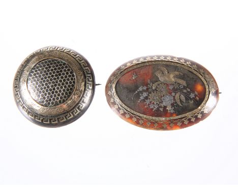 TWO 19TH CENTURY GOLD AND SILVER INLAID BROOCHES, the first oval, decorated with a bird and insect amongst a floral spray, th