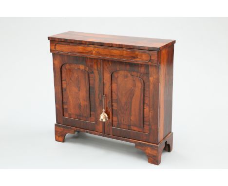 A REGENCY ROSEWOOD SIDE CABINET, the moulded frieze drawer above a pair of arch panel doors, raised on bracket feet. 85.5cm h
