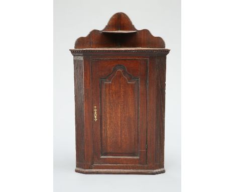 A GEORGE III OAK CORNER CUPBOARD, with fielded arch panel door flanked by fluted pilasters, beneath a dentil cornice with gal