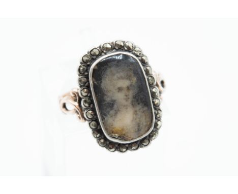 A GEORGIAN CUT-STEEL SET MOURNING RING, the oval mount with glass locket encasing the portrait of a lady, within a surround o