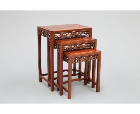 A NEST OF THREE CHINESE HARDWOOD TABLES, each with rectangular panel-moulded top above a fretwork frieze of fruiting vine, ra