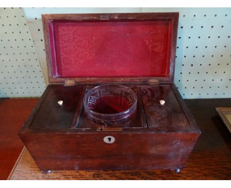 A mahogany tea caddy of sarcophagus form on bun feet, having mother of pearl escutcheon, glass mixing bowl and twin compartme