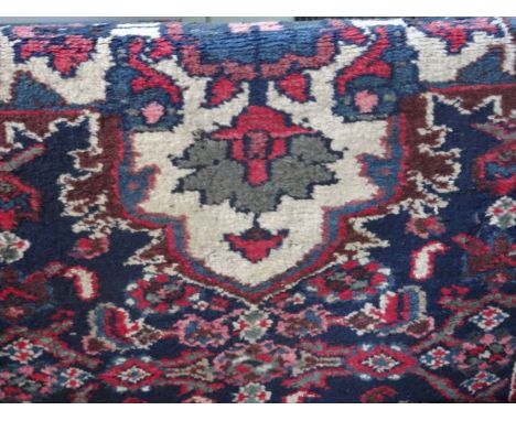 A handmade Persian carpet, having stylized floral forms on a blue ground, 172cm x 90cm.
