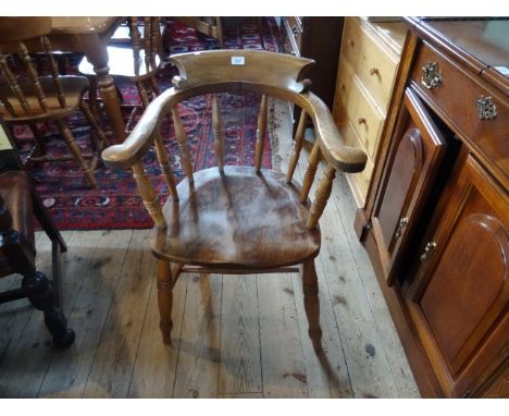 An oak smokers bow chair, having turned slats on four turned supports united by H-stretcher.