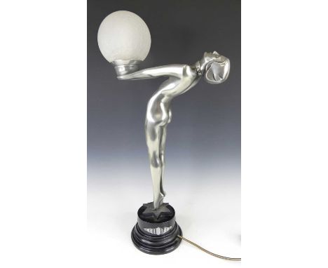 A large contemporary silvered composite table lamp in the Art Deco style, modelled as a nude female standing figure having ar