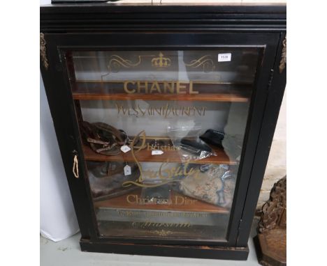 Ebonised pier cabinet with gilt metal mounts, the glazed door stencil decorated ' Chanel ', ' Yves Saint Laurent ', ' Christi