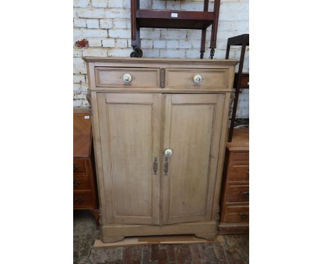 19th Century pine low wardrobe with two short drawers above two panelled doors with later ceramic knob handles, on shaped pli