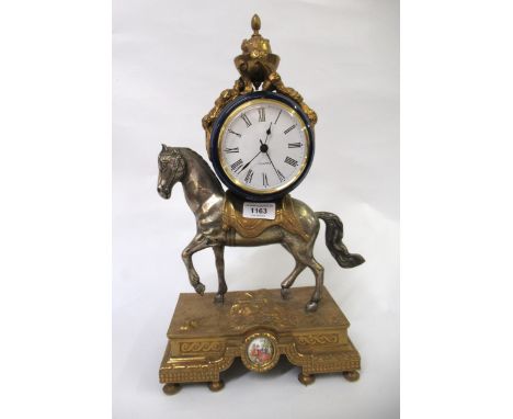 20th Century silvered and gilt metal, porcelain mounted mantel clock, the circular dial with quartz movement held aloft on ho