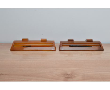 A pair of art deco Caracraft butterscotch phenolic Bakelite ink wells, with two pens, one stand with a cover loose, one ink p