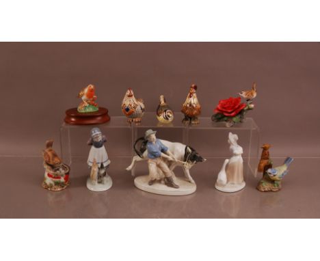 A collection of ceramic animals and figural groups, including a Royal Crown Derby enamel bird paperweight, three porcelain gr