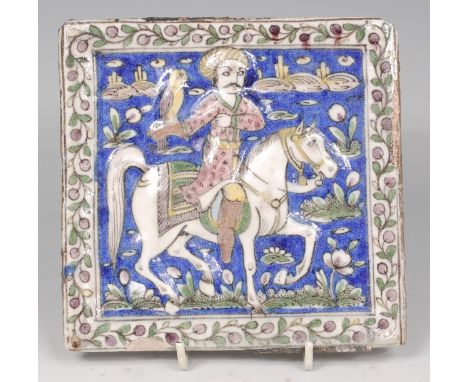 An Isnik glazed pottery tile, probably 18th century, depicting mounted hunter with hawk, all within trailing leaf and flower 