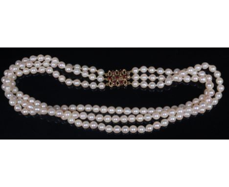 A cultured pearl triple string and knotted choker, having 9ct gold and garnet set lattice worked clasp, 36cm, each pearl dia.