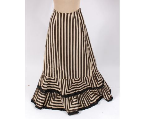 A circa 1900 cotton sateen skirt, printed in a black and white stripe, with patched work flounces, trimmed with black ribbon;