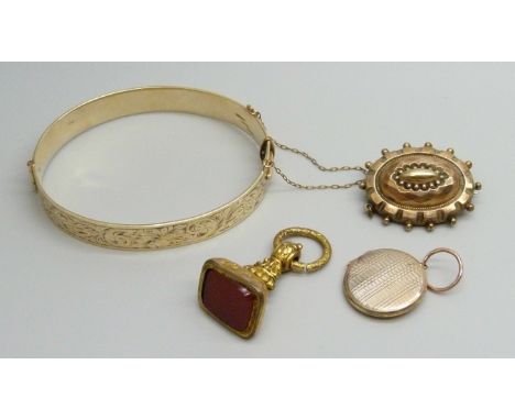 A 9ct gold metal core bangle, a gilt metal fob, a yellow metal memorial brooch and a yellow metal locket
