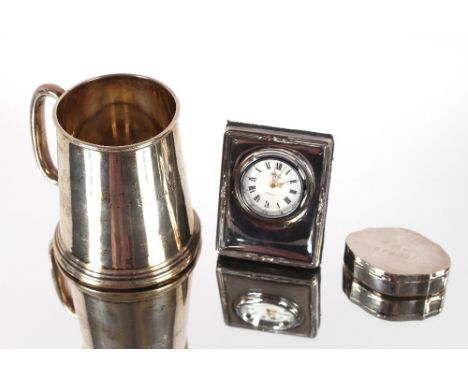A small silver Christening mug,&nbsp;Birmingham 1927;&nbsp;a modern silver pill box and a silver mounted mantel clock (3)