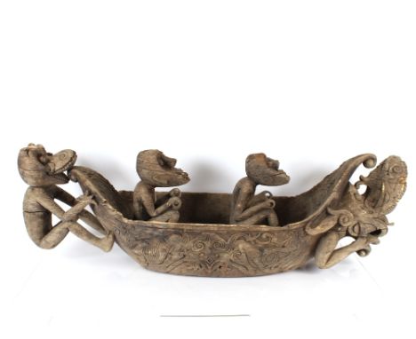 An unusual Ethnic carved softwood model of a dugout canoe with seated grotesque figures and beast head terminal AF, 152cm lon