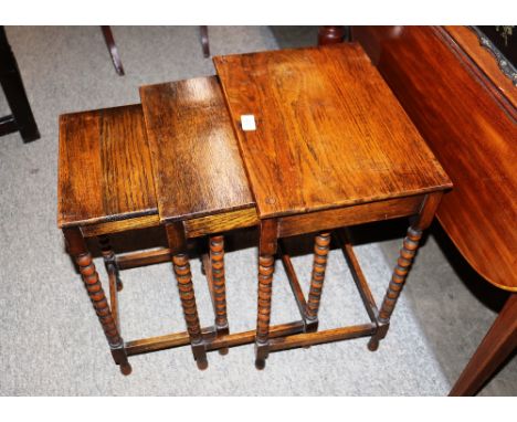A nest of three mid-20th Century oak occasional tables, raised on bobbin turned supports, 42cm wide