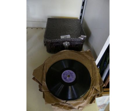 A vintage small travelling record player and accompanying records 
