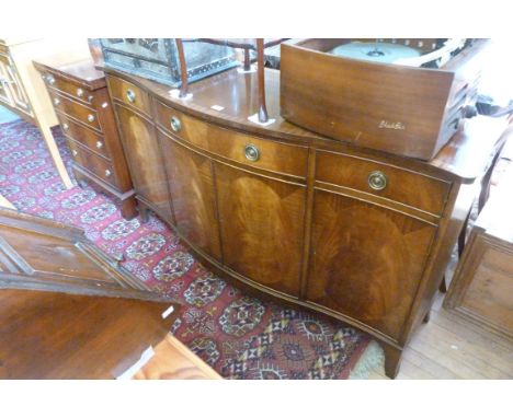 A reproduction mahogany serpentine front sideboard with three drawers over four doors, raised on bracket feet 
