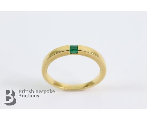 A contemporary 18ct yellow gold and emerald ring. The ring set with a square-cut emerald 2 x 3mm, size M+, 3.7 gms.&nbsp;