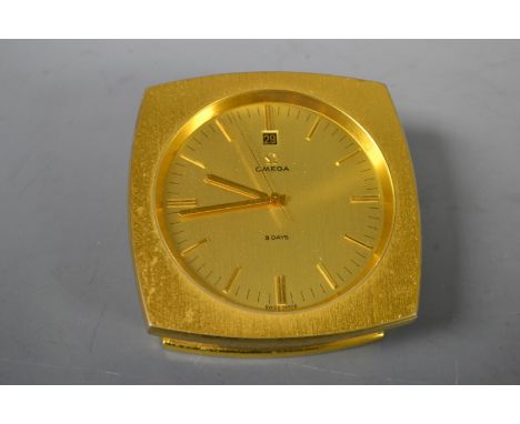 A 1960s Omega eight day lacquered brass desk clock, circular champagne dial, baton indicators, date apperture, seconds hand, 