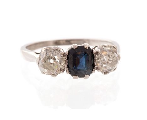 A sapphire and diamond three-stone platinum ring, central octagonal step-cut blue sapphire approx 6mm x 5mm, and two off-roun